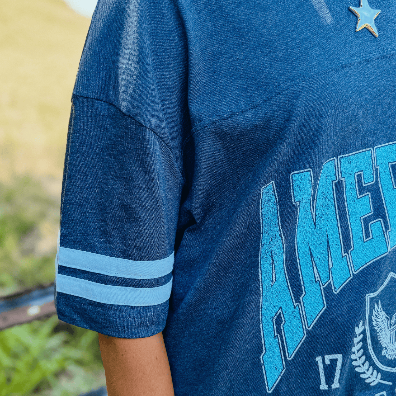 Land of the Free jersey tee in navy blue with white stripes and "AMERICA 1776" printed on the front.