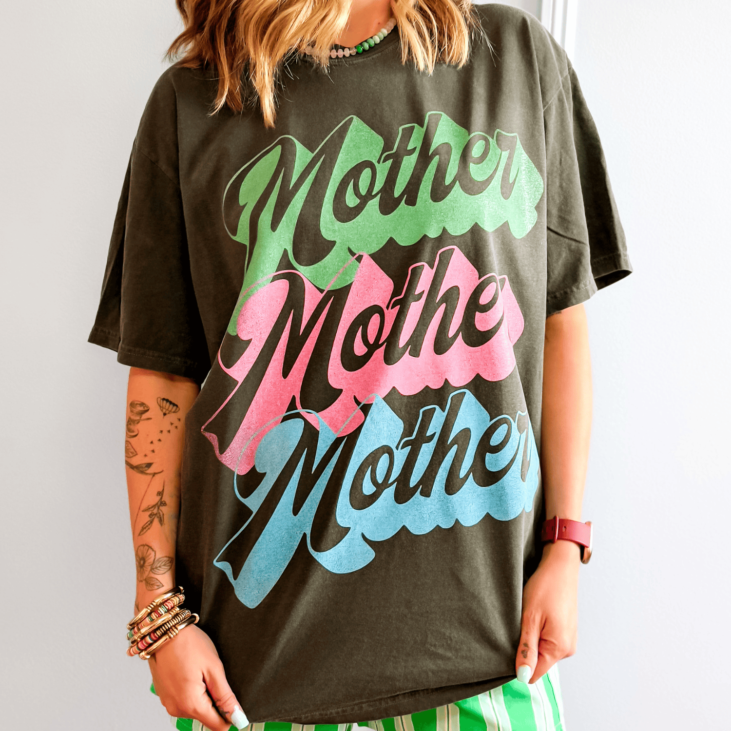 Person wearing a black t-shirt with 'Mother' printed in colorful letters.