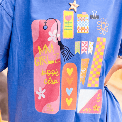 Blue Book Club Tee featuring colorful graphic designs, including flowers, hearts, and a tassel bookmark.