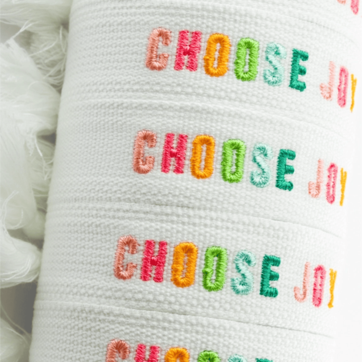Choose Joy embroidered bracelet featuring colorful text on a white fabric band.
