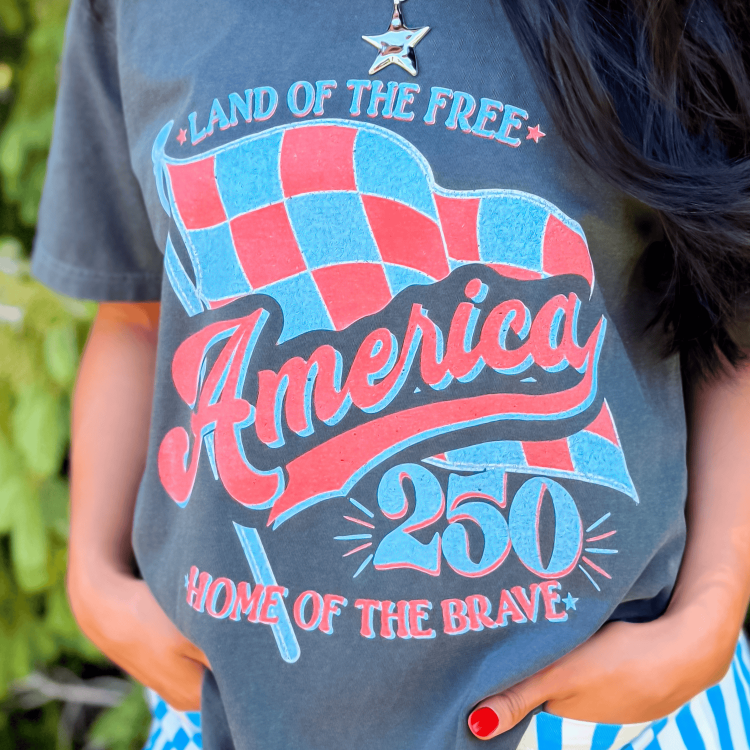 Gray t-shirt featuring a red and blue checkerboard design with "America 250" and "Land of the Free" text.