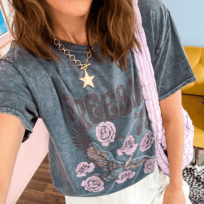 Gold star charm necklace worn with a faded graphic t-shirt featuring roses and an eagle design.